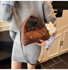 Detailed close-up of brown leopard print handbag with bow detail and plush toy charm