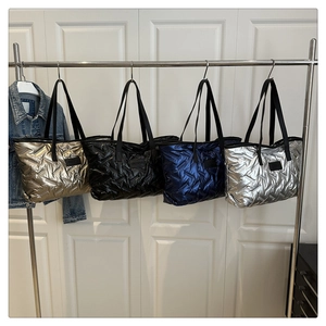 Détail de sacs fourre-tout matelassés en couleurs métallisées sur un présentoir