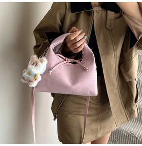 Close-up of pink matte bow handbag with plush bear charm and adjustable strap detail