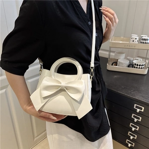 White fashion mini handbag with large bow accent and detachable strap shown on a model