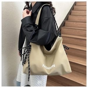 Detail of beige large capacity tote bag with fashion text and striped rope shoulder strap