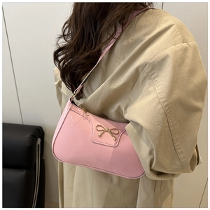 Gros plan du sac baguette en cuir verni rose avec un nœud métallique doré élégant