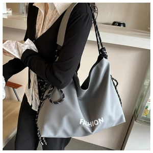 Detail of grey nylon tote bag with Fashion lettering and woven shoulder strap on model