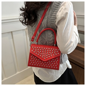 Red envelope handbag with silver rivet studs shown in a lifestyle setting