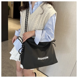 Detail of black nylon tote bag featuring thick woven rope handles and Fashion print
