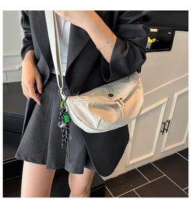 Detail view of cream nylon crossbody bag with black braided cord and double zippers