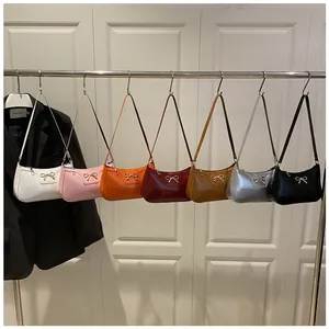 Detail view of seven colorful patent leather baguette bags with golden bow metal accents