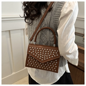 Detail of vintage brown crossbody bag with silver rivets and sleek round handle
