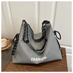 Detail der grauen Stoff-Tote-Bag mit weißem FASHION-Schriftzug und geflochtenen Seilgurten