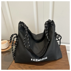 Detail der schwarzen Nylon-Tasche mit FASHION-Aufdruck und gewebtem Schultergurt