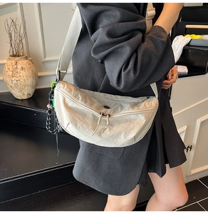 Close-up of lightweight off-white dumpling bag with dual zippers and wide strap