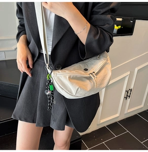 Close-up of lightweight white nylon crescent bag with stylish green pendant detail