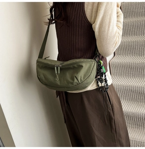 Detail van de legergroene nylon halve maan crossbodytas met decoratieve smiley hanger