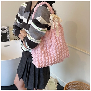 Detail of pink bubble texture tote bag with a beige lace bow on the shoulder strap
