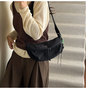 Detailed side view of black lightweight nylon crossbody bag on model for fit and size