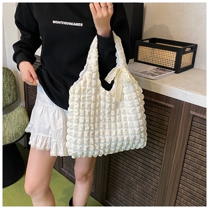Close-up of white bubble texture fabric with a beige lace bow detail on a tote bag