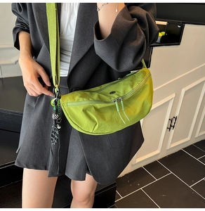 Model wearing a bright lime green nylon dumpling bag with adjustable strap and charm