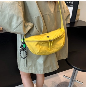 Bright yellow nylon dumpling bag detail with woven charm and circular metal logo