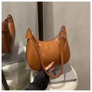 Detail of brown faux leather baguette bag with silver hardware on a modern pedestal