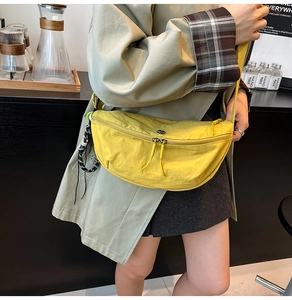 Close-up of vibrant yellow nylon crescent crossbody bag featuring dual zippers and woven detail