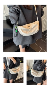 Macro-opname van de crème halve maan crossbodytas met nylon textuur en geweven hanger