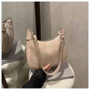 Detail view of a beige leather hobo bag with silver hardware on a luxury display pedestal