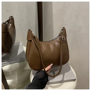Detail of a brown dumpling bag with silver zipper and matte leather in a mirror setting