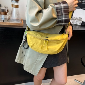 Minimalist yellow nylon crescent bag for women, shown on shoulder for daily commuting