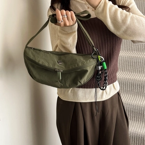 Army green nylon crescent crossbody bag with adjustable strap and decorative charms