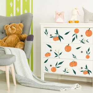 Fresh orange and green leaf wall stickers applied to a white dresser in a cozy room