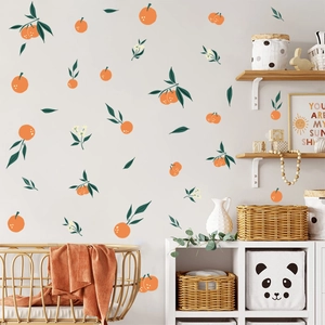 Detailed view of hand-painted orange stickers with leaves and flowers on a nursery wall