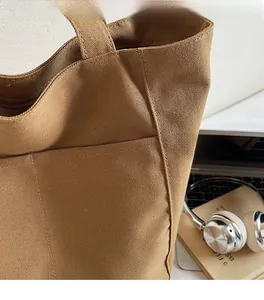 Detail of a brown canvas tote bag showing thick texture, side pocket, and fine stitching