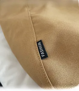 Detailed close-up of khaki canvas tote stitching and woven fashion label on the side