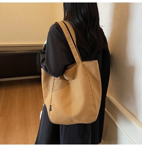 Detail of khaki canvas tote bag featuring a front pocket and FASHION label on the side
