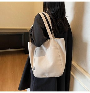 Close-up of beige canvas tote bag showing the practical front pocket and durable straps