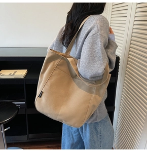 Khaki large capacity canvas tote bag with fashion label shown on model for daily use