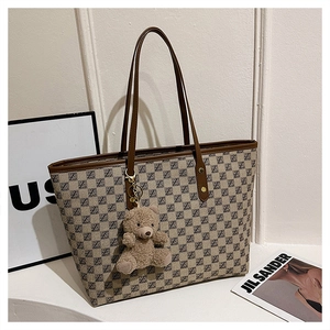 Detail of vintage tote bag featuring brown monogram pattern and cute plush bear charm