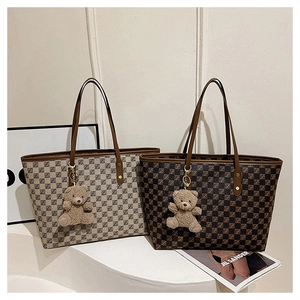 Detail view of large tote bags with checkered texture and plush bear pendants