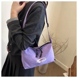 Sac bandoulière en nylon violet avec sangle réglable et logo porté par un mannequin