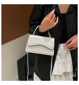 Détail du sac en cuir PU blanc avec surpiqûres ondulées et poignée en métal doré