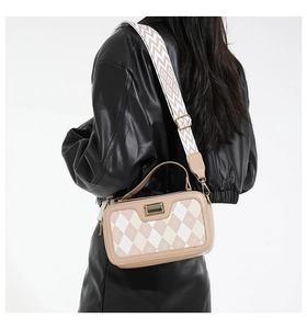 Detail of beige quilted crossbody bag featuring gold hardware and wide geometric strap