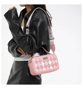 Pink checkered crossbody bag with geometric woven strap and metallic accent