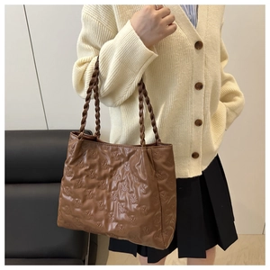 Close-up of brown tote bag with quilted bear pattern and woven rope handles