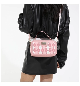Detail of pink argyle crossbody bag with wide patterned strap and gold metal hardware