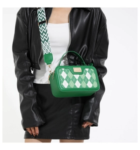 Detail of green checkered small square bag with geometric wide strap on a model