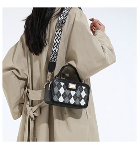 Detail van ruitjes schoudertas met geometrische riem gedragen op een klassieke trenchcoat