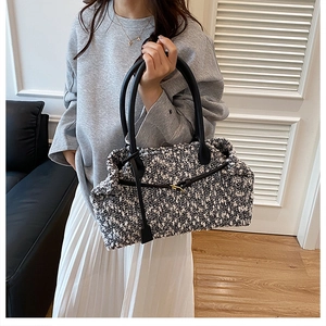 Detail of black and white tweed tote bag with slim leather handles and gold buckle