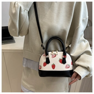 Sac coquille tendance avec imprimés cerises et poignées noires en situation réelle