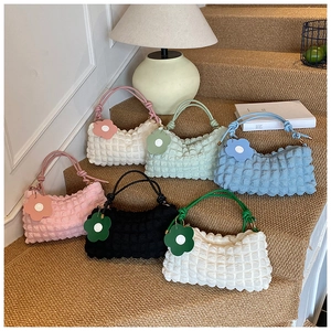 Détail de sacs à bandoulière colorés à texture bulle avec breloques fleurs sur marches