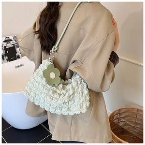 Détail du sac nuage plissé vert clair avec une breloque fleur assortie sur la bandoulière